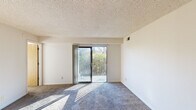 This single-floor residence at 550 Anchor Dr in Cincinnati, Ohio, offers a straightforward and functional layout designed to maximize usable living space. The floor plan, as revealed in the 3D model, includes a living area, kitchen, multiple bedrooms, and connecting hallways that create an efficient flow throughout the unit.

The living room is a generously sized space finished with plush blue-grey carpeting and a textured ceiling. A sliding glass door opens directly onto a private balcony, allowing abundant natural light to fill the room and providing views of surrounding greenery. A ceiling fan and a wood-toned entry door add practical and visual detail to the space.

The bedrooms are carpeted in warm neutral tones and feature textured ceilings consistent with the rest of the unit. Each room benefits from natural light through standard windows fitted with horizontal blinds that frame views of the outdoors. One bedroom includes a built-in closet with a wood-panel sliding door, offering convenient storage.

The kitchen area, visible in the 3D overview, includes appliances and cabinetry positioned along the perimeter. Neutral wall colors are consistent throughout, contributing to a clean and cohesive aesthetic across all rooms.