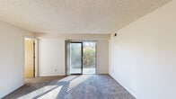 This single-floor residence at 550 Anchor Dr in Cincinnati, Ohio, offers a straightforward and functional layout designed to maximize usable living space. The floor plan, as revealed in the 3D model, includes a living area, kitchen, multiple bedrooms, and connecting hallways that create an efficient flow throughout the unit.

The living room is a generously sized space finished with plush blue-grey carpeting and a textured ceiling. A sliding glass door opens directly onto a private balcony, allowing abundant natural light to fill the room and providing views of surrounding greenery. A ceiling fan and a wood-toned entry door add practical and visual detail to the space.

The bedrooms are carpeted in warm neutral tones and feature textured ceilings consistent with the rest of the unit. Each room benefits from natural light through standard windows fitted with horizontal blinds that frame views of the outdoors. One bedroom includes a built-in closet with a wood-panel sliding door, offering convenient storage.

The kitchen area, visible in the 3D overview, includes appliances and cabinetry positioned along the perimeter. Neutral wall colors are consistent throughout, contributing to a clean and cohesive aesthetic across all rooms.