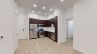 This single-floor residence presents a clean, contemporary design throughout its well-appointed layout. The kitchen serves as a functional centerpiece, outfitted with rich dark espresso cabinetry that extends to the ceiling, a full suite of stainless steel appliances including a gas range, built-in microwave, French door refrigerator with ice and water dispenser, and dishwasher. White countertops and a subway tile backsplash provide a crisp contrast, while light wood-style flooring ties the kitchen and adjacent living areas together seamlessly. Recessed lighting illuminates the space efficiently throughout.

The bedrooms are carpeted for comfort, each featuring ample closet space, including a walk-in closet in one room. The rooms are finished with crisp white walls and offer a neutral, versatile backdrop. A window in one bedroom allows for natural light to filter in.

Two bathrooms serve the residence: one features a fully tiled glass-enclosed walk-in shower with grab bars and mosaic tile flooring, while the second includes a soaking tub with a tiled surround and a curved shower rod. Both bathrooms carry a consistent neutral palette with light tile finishes and wood-style flooring. The overall aesthetic is modern, clean, and move-in ready.