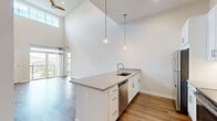 Located at 409 East Butler Avenue in New Britain, PA, this thoughtfully designed 2-bedroom, 2-bathroom residence offers a bright and contemporary living experience across a well-utilized single floor. The open-concept kitchen and living area immediately impresses with dramatic soaring ceilings and abundant natural light. The kitchen is outfitted with crisp white cabinetry, quartz-style countertops, a full suite of stainless steel appliances including a refrigerator, range, microwave, and dishwasher, and a large peninsula island with pendant lighting overhead. Rich hardwood-style flooring runs throughout the main living areas, complementing the clean, neutral palette. The spacious living room opens directly to a private balcony through sliding glass doors, offering pleasant outdoor views. The primary bedroom is generously sized, featuring plush carpeting, tall ceilings, a large window with ample natural light, and a dedicated closet with built-in shelving. The primary bathroom includes a double-sink vanity with white cabinetry, a walk-in shower, and large-format tile flooring. The second bedroom also features carpet and its own closet. Additional highlights include a utility room and a ceiling fan in the living area, rounding out a polished and functional home.