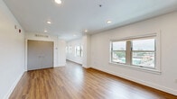 Located at 3835 Main St in Kansas City, Missouri, Unit 1008 is a thoughtfully designed single-floor residence that makes efficient use of its space. The open-concept living area is finished with warm wood-tone laminate flooring and crisp white walls, creating a bright and welcoming atmosphere. Recessed ceiling lighting adds a clean, modern touch throughout. Windows allow natural light to fill the space while offering views of the surrounding Kansas City cityscape.

The galley-style kitchen is well-appointed with white cabinetry, sleek gray quartz countertops, a white subway tile backsplash, and a full suite of stainless steel appliances, including an electric range, built-in microwave, dishwasher, and refrigerator. A stainless steel sink with a modern faucet completes the functional layout, which flows seamlessly toward the living area.

The bathroom features a clean, contemporary design with large-format tile surrounding a walk-in shower enclosed by a frameless sliding glass door. Wood-tone flooring, a modern vanity with a quartz countertop, and chrome fixtures give the space a polished, upscale feel. Overall, the unit presents a cohesive modern aesthetic with quality finishes throughout.