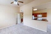Located in Gonzales, Louisiana, this two-story residence offers a well-organized layout across two levels. The ground floor houses a private garage equipped with an automatic opener, built-in shelving tracks, and an electrical panel — providing secure parking and additional storage space.

The main living area on the upper floor features an open-concept design that connects the kitchen and living space. The kitchen is outfitted with warm-toned wood cabinetry, granite-look countertops, a peninsula with a sink, and white appliances including a refrigerator, electric range, and over-the-range microwave. Hardwood-style flooring runs through the kitchen, while plush carpeting extends throughout the living and bedroom areas.

Both bedrooms are comfortably sized, each featuring ceiling fans with light kits, neutral beige walls, and windows that allow natural light and outdoor views. The primary bedroom includes access to a dedicated walk-in closet with built-in wire shelving on multiple walls, offering generous storage capacity.

The bathroom features a full tub-and-shower combination with white tile surround, a curtain rod, and tile flooring. A staircase connects the two levels, completing this functional and practical two-story layout.