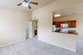 Located in Gonzales, Louisiana, this two-story residence offers a well-organized layout across two levels. The ground floor houses a private garage equipped with an automatic opener, built-in shelving tracks, and an electrical panel — providing secure parking and additional storage space.

The main living area on the upper floor features an open-concept design that connects the kitchen and living space. The kitchen is outfitted with warm-toned wood cabinetry, granite-look countertops, a peninsula with a sink, and white appliances including a refrigerator, electric range, and over-the-range microwave. Hardwood-style flooring runs through the kitchen, while plush carpeting extends throughout the living and bedroom areas.

Both bedrooms are comfortably sized, each featuring ceiling fans with light kits, neutral beige walls, and windows that allow natural light and outdoor views. The primary bedroom includes access to a dedicated walk-in closet with built-in wire shelving on multiple walls, offering generous storage capacity.

The bathroom features a full tub-and-shower combination with white tile surround, a curtain rod, and tile flooring. A staircase connects the two levels, completing this functional and practical two-story layout.