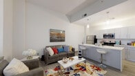 This single-floor unit at 901 S National Ave in Springfield, Missouri, presents a modern, thoughtfully designed living space with a clean aesthetic and functional layout. The open-concept living and kitchen area serves as the heart of the unit, featuring wood-look flooring, elevated ceilings, and large windows that allow natural light to fill the space while offering views of the surrounding cityscape.

The kitchen is well-appointed with crisp grey cabinetry, light quartz countertops, stainless steel appliances including a refrigerator, electric range, and built-in microwave, and a peninsula with bar seating that doubles as a dining and social hub. Pendant lighting above the peninsula adds a refined touch to the space.

The living area accommodates comfortable seating and benefits from multiple windows fitted with blinds, creating a bright yet controllable environment. Two bedrooms provide private retreats, each with wood-look flooring and window access to natural light.

The bathroom is finished with large-format tile flooring, a grey vanity with a white countertop, an integrated sink, and a large mirror. Throughout the unit, a neutral color palette of whites and greys creates a cohesive, modern ambiance suited for everyday living.
