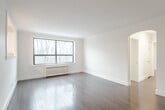 Located at 110 South Forster Park in Oakville, Ontario, this 2-bedroom, 1-bathroom unit offers a well-organized layout across a single floor. The combined living and dining area is bright and airy, featuring hardwood flooring, clean white walls, crown moulding, and large black-framed windows that frame treetop views and fill the space with natural light. A radiator beneath the windows provides classic in-unit heating. An elegant arched passageway connects the living area to the hallway, adding a touch of architectural character.

The kitchen is efficiently designed with white cabinetry, a double-basin sink, and a window overlooking the surrounding greenery. A pass-through window opens to the dining area, enhancing the sense of connectivity between the kitchen and living spaces. The unit's tile flooring in the kitchen provides a practical contrast to the hardwood found throughout the rest of the home.

Both bedrooms are comfortably proportioned, with hardwood floors and windows offering wooded outdoor views. The primary bedroom features two closets, providing ample storage. The bathroom is clean and functional, finished with neutral tile flooring, a white vanity, and a combined tub-shower unit. This unit presents a tidy, move-in-ready space in a natural Oakville setting.