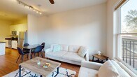 Located at 700–708 N Washington St in Alexandria, VA, this one-bedroom, one-bathroom residence offers a well-designed layout that maximizes every inch of its comfortable footprint. The open-concept kitchen flows seamlessly into the living and dining area, creating a bright, connected space ideal for everyday living. The kitchen is outfitted with white shaker cabinetry, rich dark granite countertops, a full suite of stainless steel appliances including a refrigerator, range, microwave, and dishwasher, and a peninsula that provides additional prep and seating space. Hardwood flooring runs throughout the main living areas, complementing the warm, neutral color palette. The living room is bathed in natural light from large windows with views of the surrounding Alexandria streetscape, and a ceiling fan adds comfort overhead. Track lighting in the kitchen and dining area offers versatile illumination. The bedroom features plush carpeting, a window with neighborhood views, and a stylish sliding barn door that opens to a dedicated closet. The bathroom includes tile flooring, a granite-topped vanity with an oversized mirror, and a clean, modern finish. A hallway entry with additional storage doors and a utility closet rounds out this thoughtfully arranged home.