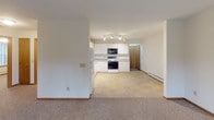 Located at 5201 Sherman St in Wausau, Wisconsin, this single-floor unit offers a practical and comfortable layout well-suited for everyday living. The kitchen is a functional highlight, featuring white cabinetry with ample storage, gray laminate countertops, tile flooring, and a full suite of appliances including an electric range, over-the-range microwave, refrigerator, and dishwasher. Track lighting illuminates the workspace efficiently. The kitchen opens toward the living area, which is finished with neutral carpet and includes a wall-mounted air conditioning unit and a sliding glass door that provides direct outdoor access and views of surrounding greenery, bringing in natural light and a pleasant connection to the outdoors. The bedrooms are carpeted and share a clean, simple aesthetic, each featuring a ceiling fan with light fixture, a window overlooking outdoor foliage, and baseboard heating. The full bathroom is well-appointed with a tub and shower combination, a single vanity with storage, a mirrored medicine cabinet, and tile flooring. Throughout the unit, a consistent neutral color palette and baseboard heating create a cohesive, understated atmosphere.