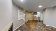 This single-floor residence is designed with an open, functional layout that connects the main living and kitchen areas seamlessly. The living room is a standout space, featuring rich wood-look flooring, neutral gray walls, a textured ceiling, and a tile-surround wood-burning fireplace flanked by a sliding glass door that invites natural light and outdoor views. A ceiling fan overhead adds both comfort and character.

The kitchen is efficiently arranged around a peninsula with light countertops, white cabinetry, and stainless steel appliances including an electric range, built-in microwave, dishwasher, and refrigerator. A window above the sink provides additional natural light. An adjacent area with built-in wall shelving adds convenient storage and display space.

The bedrooms are carpeted for comfort, each featuring neutral tones, textured ceilings, and windows or sliding glass doors offering outdoor views. One bedroom includes a closet with bifold doors.

Two full bathrooms serve the unit. One features a tub-shower combination with tiled surround and a single vanity, while the second offers a glass-enclosed walk-in shower, a wide vanity with white cabinetry, and wood-look tile flooring — both finished in a clean, modern style.