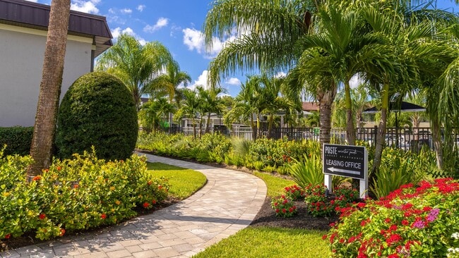 Stroll through the vibrant and lushly landscaped walkway leading to the leasing office. Surrounded by tropical plants and greenery, this inviting path sets the tone for a welcoming and serene community. - POSTE Winter Park Apartments