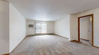 This single-floor residence features 3 bedrooms, 2 bathrooms, and a well-organized layout designed for functional living. The spacious living room is highlighted by a large sliding glass door with vertical blinds, allowing ample natural light and outdoor views, complemented by baseboard heating and a wall-mounted air conditioning unit. The carpeted living area flows into the adjacent rooms, creating a cohesive and open feel throughout.

The galley-style kitchen is efficiently designed with cream-colored cabinetry, ample counter space, tile flooring, and includes a full suite of appliances — a black gas range, white refrigerator, dishwasher, and an overhead exhaust hood.

The primary bedroom is generously sized, featuring carpet flooring, a window with natural light, baseboard heating, and access to a dedicated walk-in closet outfitted with wire shelving for organized storage. The additional bedrooms are carpeted and well-proportioned, each with closet access and baseboard heating.

The two bathrooms are finished with tile flooring and wood-accented cabinetry. One features a full tub-shower combination, while the second offers a standalone walk-in shower — both include single-sink vanities with mirrors. The textured ceilings and warm wood trim details carry consistently throughout the unit, lending a uniform and tidy aesthetic.