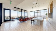 Located at 817 N 6th St in downtown Phoenix, this expansive single-floor space offers a sophisticated, multi-functional environment spread across a generous footprint. Floor-to-ceiling curtain wall glazing wraps the perimeter, flooding the interior with abundant natural light and framing sweeping panoramic views of the Phoenix skyline and the surrounding mountain ranges.

The open layout is thoughtfully organized into distinct functional zones. A fully equipped kitchen and bar anchors one end of the space, featuring a dramatic waterfall-edge white stone island with bar seating, warm wood cabinetry, open shelving, a tile backsplash, and sculptural pendant lighting. Adjacent to the kitchen, a dining and lounge area provides ample seating with a mix of chairs and tables suited for both casual gatherings and formal meetings.

A residential-style lounge area features plush sectional and accent seating arranged around coffee tables, all oriented toward the expansive exterior views and an outdoor terrace accessible through glass sliding doors. Throughout the space, geometric linear ceiling fixtures provide accent lighting, complementing the recessed lighting above.

Private glass-enclosed offices line one side of the floor, offering visual transparency while maintaining acoustic separation. Light tile flooring and neutral tones throughout contribute to a bright, airy, and refined atmosphere befitting a premier high-rise location in the heart of Phoenix.