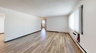 Located at 124 Capitol View Terr in Madison, WI, this 2-bedroom, 1-bathroom unit offers a clean, efficiently designed single-floor layout. Consistent hardwood-style flooring runs throughout all rooms, complemented by crisp white walls and bold black door trim that create a modern, cohesive aesthetic. Textured ceilings are found in several areas, adding visual character overhead.

The spacious living room is a standout area, featuring a large window with vertical blinds that allows ample natural light, a baseboard heating system, and a wall-mounted air conditioning unit for year-round comfort. The kitchen is well-appointed with white shaker-style cabinetry, dark stone countertops, a stainless steel electric range, an under-cabinet range hood, and a double sink — all illuminated by overhead fluorescent lighting.

The primary bedroom offers a generous footprint, featuring a double-panel closet with bold black trim framing, hardwood-style floors, and natural light. The second bedroom also includes a window with exterior views, baseboard heating, and a textured ceiling. The full bathroom is finished with a white vanity, under-sink storage, a combined tub and shower, and backlit mirror — all in a clean, bright white palette.