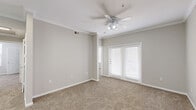 Located at 1648 N Zaragoza Rd in El Paso, TX, this two-bedroom, two-bathroom residence offers a comfortable and functional single-floor layout. The open living area is finished with plush carpet, crown molding, and a ceiling fan with integrated lighting, creating a welcoming atmosphere. French doors allow natural light to fill the space and provide access to the outdoors. A chandelier accents the adjacent dining area, which connects seamlessly to the kitchen. The kitchen features white cabinetry, white countertops, a double-basin sink, wood-look vinyl flooring, and black appliances including a range, built-in microwave, and dishwasher. A door from the kitchen leads directly to the in-unit laundry area, which includes a Whirlpool top-load washer and overhead wire shelving. The primary bedroom is generously sized with a ceiling fan and its own walk-in closet equipped with wire shelving on multiple levels. The two bathrooms offer wood-look flooring, white vanities, and tiled tub-shower combinations. The second bedroom is carpeted and well-proportioned with its own closet. Neutral tones throughout lend a clean, move-in-ready appeal to this well-appointed El Paso residence.