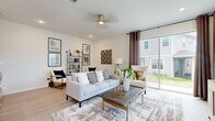Located at 1244 Eagle Branch Ln in Davenport, Florida, this two-story home offers a well-designed layout with modern finishes throughout. The open-concept main floor centers around a striking kitchen, featuring crisp white shaker cabinetry, quartz countertops, a large center island, a breakfast bar with seating, stainless steel appliances including a French door refrigerator, and elegant pendant lighting. Light wood-style flooring flows seamlessly throughout the main level, enhancing the bright, airy atmosphere. Adjacent to the kitchen is a dedicated dining area with a large window that fills the room with natural light, and a comfortable living room with sliding glass doors that open to outdoor views. The living room is generously proportioned, offering ample space for relaxation. A powder room on the main floor provides added convenience for guests. Upstairs, the primary bedroom is a serene retreat highlighted by a tray ceiling, striped accent wall, and large windows with natural light. Additional bedrooms include a warmly decorated room with soft accent tones and a third bedroom with angled ceilings and a playful character. Each room features light flooring and ceiling fans. The home's cohesive design, neutral palette, and modern touches make it a functional and stylish residence.