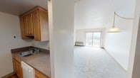 Located at 9231 Independence Blvd in Parma, Ohio, this single-floor unit offers a functional and well-organized layout. The living area is generously sized, finished with plush carpeting and bathed in natural light through a large sliding glass door fitted with vertical blinds, which opens to an outdoor balcony. A wall-mounted heating unit sits beneath the slider, and a decorative pendant light adds a warm touch to the dining area nearby.

The galley-style kitchen features warm oak cabinetry, laminate countertops, a stainless sink, and a coil-burner electric range. Wood-look flooring runs throughout the kitchen, and a pass-through window connects the space to the living and dining area, enhancing the open feel. A set of dark sliding closet doors provides ample storage just off the kitchen entry.

The bedroom is carpeted and bright, with a large window dressed in vertical blinds that allows plenty of natural light to filter in. The full bathroom is finished with classic yellow mosaic tile flooring and coordinating wall tile surround, a full soaking tub with grab bars, a toilet, and a wood-vanity with a single sink. The unit's compact, efficient design makes practical use of every area throughout.