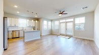 This well-appointed single-floor residence offers a clean, modern aesthetic defined by light tones, quality finishes, and an abundance of natural light. The open-concept living and kitchen area serves as the heart of the home, where light hardwood flooring flows seamlessly throughout. A ceiling fan anchors the airy living space, which features French doors that invite natural light and provide access to the outdoors.

The kitchen is a standout feature, boasting crisp white shaker-style cabinetry extending to the upper walls for generous storage, a full suite of stainless steel appliances including a refrigerator, range, microwave, and dishwasher, and a central island topped with elegant granite countertops. Pendant lighting above the island adds a refined touch, while a subway tile backsplash and a window over the sink complete the space.

Two well-sized bedrooms offer plush carpeting, ceiling fans, and blinds-fitted windows that allow for controlled natural light. The two bathrooms echo the home's consistent style, each featuring white cabinetry, granite countertops, and hardwood-style flooring. A full bath includes a tub and shower combination, while a second bath provides a dual-sink vanity. The overall ambiance is bright, clean, and move-in ready.