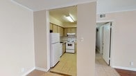 Located at 1201 N Foster Dr in Baton Rouge, Louisiana, this single-floor unit offers a practical and comfortable layout designed for everyday living. The open living and dining area features a combination of warm hardwood-style flooring and light ceramic tile, with recessed lighting and track lighting adding a modern touch. Natural light filters in through blinded windows, creating a bright and welcoming atmosphere throughout.

The kitchen is accessible via a wide doorway opening from the main living area, equipped with light wood cabinetry, a tiled backsplash, white appliances including a refrigerator, electric range, and dishwasher, all set over durable tile flooring. An adjacent dining or utility nook connects seamlessly to the kitchen.

The bedrooms are carpeted and generously proportioned, each featuring ceiling fans, natural light from windows, and louvered bifold closet doors with built-in shelving for ample storage. The primary bedroom connects to a dedicated vanity area with a wide mirror, Hollywood-style lighting, white cabinetry, and access to a walk-in closet with shelving.

The bathrooms are finished with tile flooring and walls, featuring a combined tub and shower, toilet, and clean white fixtures. Crown molding runs throughout the unit, adding a refined architectural detail to the overall neutral and inviting interior palette.
