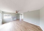 This single-story, 2-bedroom, 3-bathroom unit offers a well-designed layout with a cohesive aesthetic throughout. The living room serves as the heart of the home, featuring light wood-style flooring, soft sage-green walls, a textured ceiling, a ceiling fan with light, and a striking stacked-stone fireplace as a focal point. Large windows and a sliding glass door fill the space with natural light and provide access to one of two outdoor patios. The galley-style kitchen is bright and modern, outfitted with white shaker cabinetry, white quartz countertops, stainless steel appliances including a range, microwave, and refrigerator, a single-basin sink, and a skylight overhead. The dining room flows naturally from the kitchen, maintaining the same warm flooring and neutral palette. Both bedrooms are comfortably sized, with the primary bedroom offering its own ceiling fan and a patio access point via a sliding glass door. Each bedroom includes a closet with white panel bifold doors. The three bathrooms feature clean, white tub-shower combinations with brushed nickel fixtures. A dedicated laundry area and a hallway with additional closets add everyday convenience throughout this thoughtfully laid-out home.