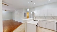 This single-floor residence offers a thoughtfully designed layout across two bedrooms and two bathrooms. The open-concept kitchen and living area serves as the heart of the home, where the kitchen stands out with quartz countertops featuring subtle marble-like veining, white cabinetry, a peninsula with pendant lighting, stainless steel appliances, and a decorative tile backsplash. Large-format tile flooring anchors the kitchen area, while rich hardwood flooring extends through the living room and bedrooms, adding warmth throughout.

The living room is bright and airy, equipped with a ceiling fan and sliding glass doors that open to a patio overlooking lush tropical greenery. The primary bathroom is a standout feature, finished entirely in marble-style tile — from floor to ceiling — and includes a double-sink vanity with brushed nickel fixtures and a walk-in shower with a rainfall head and built-in niche. The bedrooms are comfortable and well-lit, each with ceiling fans. One bedroom includes a walk-in closet with wire shelving on multiple sides, providing generous storage. The second bedroom features its own closet with louvered doors, visible from the main living area. Neutral tones and clean finishes give the entire space a cohesive, modern aesthetic.