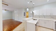This single-floor residence offers a thoughtfully designed layout across two bedrooms and two bathrooms. The open-concept kitchen and living area serves as the heart of the home, where the kitchen stands out with quartz countertops featuring subtle marble-like veining, white cabinetry, a peninsula with pendant lighting, stainless steel appliances, and a decorative tile backsplash. Large-format tile flooring anchors the kitchen area, while rich hardwood flooring extends through the living room and bedrooms, adding warmth throughout.

The living room is bright and airy, equipped with a ceiling fan and sliding glass doors that open to a patio overlooking lush tropical greenery. The primary bathroom is a standout feature, finished entirely in marble-style tile — from floor to ceiling — and includes a double-sink vanity with brushed nickel fixtures and a walk-in shower with a rainfall head and built-in niche. The bedrooms are comfortable and well-lit, each with ceiling fans. One bedroom includes a walk-in closet with wire shelving on multiple sides, providing generous storage. The second bedroom features its own closet with louvered doors, visible from the main living area. Neutral tones and clean finishes give the entire space a cohesive, modern aesthetic.
