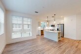 Located at 105 NE Sixth Ave in vibrant Delray Beach, Florida, this single-story, 3-bedroom, 2-bathroom home offers a clean, modern aesthetic throughout. The open-concept living and kitchen area serves as the heart of the home, featuring light wood-look flooring, crisp white walls, and an abundance of natural light streaming through large windows dressed with slatted blinds. The kitchen is thoughtfully designed with white shaker-style cabinetry, quartz countertops, a central island with built-in shelving, stainless steel appliances including a refrigerator, range, microwave, and dishwasher, and sleek pendant lighting overhead. A door off the kitchen provides convenient outdoor access. The hallway, accented with louvered closet doors, connects the main living area to the three bedrooms, each finished with the same warm wood-look flooring, neutral paint, and windows that invite natural light. The spacious primary bedroom includes a ceiling fan and dedicated closet space. Both bathrooms are finished to a high standard, with one featuring a glass-enclosed walk-in shower with large-format tile, a dual-sink vanity with white cabinetry, quartz countertops, and matte black hardware accents throughout. Two additional closets provide ample storage across the home.