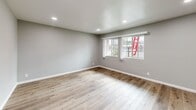 Located at 3313 N Maple Ave in Fresno, California, this single-floor, 2-bedroom, 1-bathroom home offers a cohesive and freshly updated interior. Wood-look luxury vinyl flooring runs throughout every room, providing a warm and consistent aesthetic. The living room is a bright, open space featuring recessed lighting, a ceiling fan, and large windows that invite natural light and views of the surrounding neighborhood. The kitchen is efficiently designed with white shaker-style cabinetry, gray countertops, and stainless steel appliances, including a range and over-the-range microwave. The primary bedroom is a generously proportioned retreat equipped with a ceiling fan and access to a dedicated closet with built-in shelving. The second bedroom features a large window with vertical blinds, filling the room with natural light. Both bedrooms are finished with the same neutral gray and white tones seen throughout the home. The bathroom is cleanly appointed with white cabinetry featuring matte black hardware, a white vanity, and a tub-shower combination enclosed by sliding glass doors with brushed nickel fixtures. A hallway connects the main living areas to the bedrooms, adding to the home's functional single-floor layout. The overall ambiance is modern, clean, and move-in ready.