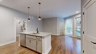 Located at 199 Dickenson St in Columbus, OH, this well-designed 2-bedroom, 2-bathroom unit offers a thoughtful single-level layout with modern finishes throughout. The open-concept kitchen serves as the heart of the home, featuring granite countertops, gray shaker-style cabinetry, stainless steel appliances, a subway tile backsplash, and a central island with a built-in sink accented by sleek pendant lighting. Warm-toned hardwood-style flooring flows through the kitchen and living areas, creating a cohesive and inviting atmosphere. The living room benefits from natural light through large windows and a glass door that opens to an outdoor area. Both bedrooms are carpeted for comfort and include walk-in closets with built-in shelving. Each bathroom is finished with marble-look tile flooring, granite-topped vanities, and matte black hardware. One bathroom features a glass-enclosed walk-in shower with white subway tile, while the other includes a soaking tub. A dedicated utility room adds everyday convenience. The unit's cool gray wall palette and consistent use of modern fixtures create a clean, contemporary aesthetic throughout.