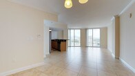 This well-appointed single-floor residence offers a thoughtfully designed open layout that maximizes both space and natural light. The expansive living and dining areas are unified by large-format porcelain tile flooring in a warm beige tone, which flows seamlessly throughout the entire unit. Crown molding adds a refined architectural touch to the main living spaces, while pendant and chandelier fixtures provide elegant overhead lighting.

Floor-to-ceiling sliding glass doors in the living area and primary bedroom frame sweeping city and treetop views, filling the interior with abundant natural light and providing direct access to the balcony. Ceiling fans in the bedrooms enhance comfort, complementing the airy, open atmosphere.

The kitchen is equipped with warm wood cabinetry, dark granite countertops, stainless steel appliances including a refrigerator, microwave, and dishwasher, and a peninsula that opens toward the main living space — ideal for both cooking and entertaining.

The bathroom features clean white cabinetry with dark granite countertops, neutral tile flooring, and a tub-shower combination, offering a functional and tidy design. Additional bedrooms are generously proportioned, each with ceiling fans and ample natural light from windows. Overall, this residence delivers a bright, clean, and functional living environment with notable city views.