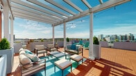 Located at 695 Atlantic St in Stamford, Connecticut, this generously sized rooftop terrace offers an impressive open-air retreat above the city. The deck is finished with warm wood-tone interlocking tiles that lend a polished, cohesive feel throughout the entire space. A prominent white pergola anchors one section of the terrace, providing partial shade and an architectural focal point, while string lights add a welcoming ambiance for evening use. The terrace is thoughtfully divided into distinct functional zones. A lounge area beneath the pergola features cushioned seating arrangements ideal for relaxed conversation, while a separate cluster of vibrant teal Adirondack chairs creates a casual gathering spot. A dedicated dining area is equipped with picnic-style bench tables and a large shade umbrella, accommodating group meals or events. Tall white planters filled with manicured greenery and colorful flowers are positioned throughout, adding natural beauty and a sense of privacy. The perimeter features low white parapet walls that frame unobstructed panoramic views of the Stamford skyline, surrounding greenery, and distant waterway. The terrace receives abundant natural light throughout the day, making it a bright and inviting outdoor destination year-round.