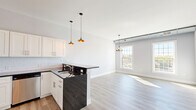 Located in the heart of Beacon, NY, this thoughtfully designed one-bedroom, one-bathroom residence offers a clean, modern aesthetic throughout its well-appointed single-floor layout. Light-toned luxury vinyl plank flooring flows seamlessly across the open-concept living and kitchen areas, complemented by soft gray walls and crisp white trim that create a bright, airy atmosphere.

The kitchen is a standout feature, showcasing white shaker cabinetry extending to the ceiling, a classic subway tile backsplash, dark granite countertops, and a peninsula with pendant lighting overhead. Stainless steel appliances, including a range, microwave, dishwasher, and refrigerator, complete this functional and stylish space.

The living room benefits from large multi-pane windows that invite an abundance of natural light and offer views of the surrounding Beacon streetscape. Exposed ductwork along the upper walls lends an industrial character to the space, nodding to the building's architectural heritage.

The spacious bedroom features multiple closet doors, light-filled windows, and the same warm flooring found throughout. The bathroom includes a tiled shower, a vanity with dark wood cabinetry, and tile flooring. In-unit laundry adds everyday convenience. Five closets throughout provide exceptional storage for a residence of this size.
