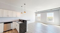 Located in the heart of Beacon, NY, this thoughtfully designed one-bedroom, one-bathroom residence offers a clean, modern aesthetic throughout its well-appointed single-floor layout. Light-toned luxury vinyl plank flooring flows seamlessly across the open-concept living and kitchen areas, complemented by soft gray walls and crisp white trim that create a bright, airy atmosphere.

The kitchen is a standout feature, showcasing white shaker cabinetry extending to the ceiling, a classic subway tile backsplash, dark granite countertops, and a peninsula with pendant lighting overhead. Stainless steel appliances, including a range, microwave, dishwasher, and refrigerator, complete this functional and stylish space.

The living room benefits from large multi-pane windows that invite an abundance of natural light and offer views of the surrounding Beacon streetscape. Exposed ductwork along the upper walls lends an industrial character to the space, nodding to the building's architectural heritage.

The spacious bedroom features multiple closet doors, light-filled windows, and the same warm flooring found throughout. The bathroom includes a tiled shower, a vanity with dark wood cabinetry, and tile flooring. In-unit laundry adds everyday convenience. Five closets throughout provide exceptional storage for a residence of this size.