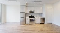 Located at 9 Saint Stevens Court in Toronto's Etobicoke neighbourhood, this well-appointed one-bedroom, one-bathroom unit offers a thoughtfully designed open-concept layout with modern finishes throughout. Light wood-tone flooring flows seamlessly from the welcoming entrance through the living, dining, and kitchen areas, creating a cohesive and airy feel. The kitchen is outfitted with stainless steel appliances — including a refrigerator, electric range, built-in microwave, and dishwasher — complemented by sleek white cabinetry, a tile backsplash, and ample counter space. Track lighting runs the length of the kitchen and living area, enhancing brightness alongside large floor-to-ceiling windows that invite generous natural light and provide open views of the surrounding neighbourhood. The bedroom features a double closet, clean white walls, and a sizable window with outdoor views. A versatile den adds functional flexibility, suitable as a home office or additional storage space. Two closets offer practical storage. The bathroom is finished with elegant marble-style tile in the glass-enclosed shower, lending a polished, upscale touch. A private balcony extends the living space outdoors. The unit's clean, contemporary aesthetic and efficient layout make it a highly functional and attractive urban residence.