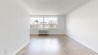 Located at 2040 Eglinton Ave W in Toronto's vibrant Eglinton West neighbourhood, this well-appointed one-bedroom, one-bathroom unit offers a thoughtfully organized layout across a single floor. The interior is finished throughout in a clean, neutral palette with crisp white walls and warm parquet wood flooring that adds character and texture to every room.

The spacious living room is a standout feature, boasting a wide, multi-pane window that frames outdoor views and floods the room with natural light. A classic radiator sits beneath the window, complementing the room's timeless feel. Crown moulding and a textured ceiling add architectural detail, while an elegant arched doorway provides a graceful transition into the rest of the unit.

The galley-style kitchen is efficiently designed with white shaker cabinetry extending to the ceiling, subway tile backsplash, a stainless steel sink, and a full suite of stainless steel appliances including a refrigerator, stove, and dishwasher. Light tile flooring keeps the space bright and easy to maintain.

The bedroom is a comfortable, well-sized room featuring parquet flooring, a built-in closet, and a window offering natural light and outdoor views, with a radiator ensuring year-round comfort.

The bathroom is finished with crisp white subway tile surrounding a full soaker tub with overhead shower, paired with a modern white vanity and chrome fixtures for a clean, polished look.