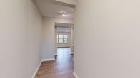 This two-story home offers a practical and modern layout across two well-proportioned floors. The main level features an open-concept kitchen, dining, and living area, anchored by a standout kitchen with rich dark cabinetry, a central island with a white countertop, stainless steel appliances, a geometric tile backsplash, and pendant lighting. Light wood-tone flooring runs throughout the main level, complementing the neutral, warm color palette. A welcoming entrance and hallway connect the main living areas, while a dedicated laundry room houses a full-size washer and dryer. The upper floor accommodates all three bedrooms, including a generously sized primary bedroom featuring a tray ceiling, plush carpet, and a pendant light fixture. Additional bedrooms offer light hardwood-style flooring and ample natural light through large windows with views of surrounding greenery. The four bathrooms are finished with contemporary fixtures, including matte black hardware, large-format gray tile surrounds in the tub-shower combinations, and white vanities with clean countertops. Two hallways ensure smooth circulation between rooms on both levels, and a dedicated closet provides additional storage. The home's cohesive design blends modern finishes with functional, comfortable living spaces.