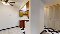 Located at 2233 N Summit Ave in Milwaukee's vibrant East Side neighborhood, this single-floor unit offers a practical and functional layout. The kitchen is efficiently designed with warm wood cabinetry offering ample upper and lower storage, a white countertop with an undermount sink, and a range. A distinctive black-and-white checkered tile floor adds a classic touch to the kitchen and entry areas, creating a visual contrast with the neutral-toned walls throughout.

The living area is open and versatile, featuring soft wall-to-wall carpeting, a ceiling fan, and easy sightlines into the kitchen, lending a connected and airy feel to the space. Baseboard heating runs along the perimeter of the rooms, ensuring efficient warmth throughout the colder Milwaukee months.

The bedroom is a quiet, well-proportioned room with plush carpeting, baseboard heating, and a window dressed with horizontal blinds that filters natural light and offers views of surrounding greenery. A second carpeted room provides additional flexible living space with its own window.

The bathroom includes a single-sink vanity with wood cabinetry, a tub-shower combination with a curtain, and a pale blue tile floor that adds a retro character. Louvered closet doors are featured throughout, contributing to the unit's cohesive, classic aesthetic.