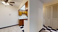 Located at 2233 N Summit Ave in Milwaukee's vibrant East Side neighborhood, this single-floor unit offers a practical and functional layout. The kitchen is efficiently designed with warm wood cabinetry offering ample upper and lower storage, a white countertop with an undermount sink, and a range. A distinctive black-and-white checkered tile floor adds a classic touch to the kitchen and entry areas, creating a visual contrast with the neutral-toned walls throughout.

The living area is open and versatile, featuring soft wall-to-wall carpeting, a ceiling fan, and easy sightlines into the kitchen, lending a connected and airy feel to the space. Baseboard heating runs along the perimeter of the rooms, ensuring efficient warmth throughout the colder Milwaukee months.

The bedroom is a quiet, well-proportioned room with plush carpeting, baseboard heating, and a window dressed with horizontal blinds that filters natural light and offers views of surrounding greenery. A second carpeted room provides additional flexible living space with its own window.

The bathroom includes a single-sink vanity with wood cabinetry, a tub-shower combination with a curtain, and a pale blue tile floor that adds a retro character. Louvered closet doors are featured throughout, contributing to the unit's cohesive, classic aesthetic.