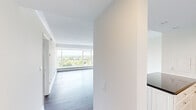 This thoughtfully designed one-bedroom, one-bathroom residence offers a well-proportioned layout across a single floor, providing comfortable and functional living space. The interior is defined by a bright, neutral palette of crisp white walls and warm hardwood flooring that flows throughout the main living areas and bedroom.

The living room is a standout feature, anchored by expansive floor-to-ceiling windows that flood the space with abundant natural light and frame panoramic treetop and skyline views, lending the room an open, airy quality. The generously sized primary bedroom mirrors this elevation, also benefiting from large windows with the same scenic outdoor vistas and rich hardwood floors.

The kitchen is well-equipped with white shaker-style cabinetry extending to the ceiling, dark granite countertops, stainless steel appliances including a range, microwave, and dishwasher, a tiled backsplash, and tile flooring. A peninsula provides additional counter and prep space.

The bathroom features a full soaking tub with a shower, framed by full-height earth-toned ceramic tile with a decorative border detail. A hallway connects the rooms efficiently, completing this cohesive and functional layout.