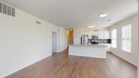 This single-floor residence offers a thoughtfully designed open-concept layout that seamlessly connects the living area and kitchen. The main living space features warm hardwood-style flooring and an abundance of natural light, courtesy of multiple large windows that offer views of the surrounding greenery. A glass-paneled door provides additional light and exterior access from the living area.

The kitchen is a standout feature, equipped with stainless steel appliances including a refrigerator, range, and over-the-range microwave. Crisp white cabinetry pairs elegantly with granite countertops and a gray subway tile backsplash. A generously sized kitchen island with a built-in sink and granite surface serves as both a functional workspace and a natural gathering point.

The bedrooms are carpeted for comfort and feature ample closet space. One bedroom includes a walk-in closet and direct access to a private en suite bathroom fitted with a vanity, walk-in shower, and a separate water closet. A second full bathroom offers a combination tub and shower, tile flooring, and a clean white vanity. The overall design palette of neutral tones and clean lines creates a bright, welcoming ambiance throughout the residence.