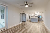 Located in Melbourne, FL, this thoughtfully designed residence offers three bedrooms and three bathrooms across a single-floor layout. The open-concept living and kitchen area serves as the heart of the home, featuring light-toned luxury vinyl plank flooring, neutral walls, and a ceiling fan that enhances the airy atmosphere. The kitchen is a standout, showcasing white upper cabinetry, gray lower cabinets, a subway tile backsplash, stainless steel appliances including a smart French door refrigerator, double wall ovens, a sleek range hood, and a large center island with a stainless farmhouse sink and pendant lighting. The bedrooms are bright and inviting, with natural light streaming through window treatments. The primary bedroom offers a generously sized walk-in closet with custom shelving and hanging rods. Bathrooms are finished with large-format gray marble-style tile, glass-enclosed walk-in showers, and brushed nickel fixtures. A dedicated laundry room adds convenience, complete with white cabinetry, quartz countertops, and a stainless utility sink. The cohesive use of neutral tones, modern hardware, and quality finishes throughout gives this residence a clean, contemporary aesthetic.
