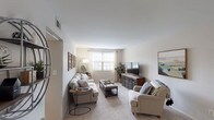 Located at Olde Hill Court in Columbus, Ohio, this single-floor unit offers a well-organized and comfortable layout designed for everyday living. The living room serves as the heart of the home, featuring soft carpeting, neutral walls, and natural light streaming through large windows with curtains. The open sightlines connect the living area to the entryway, creating a sense of flow and spaciousness throughout. A dedicated dining area sits adjacent to the kitchen, which is equipped with warm wood cabinetry, light vinyl plank flooring, a full suite of black appliances including a refrigerator, electric range, and over-the-range microwave, along with ample counter space and a sink beneath upper cabinets. The unit includes two bedrooms, each carpeted and featuring windows that bring in natural light. The primary bedroom offers generous proportions and a calm, neutral palette, while the second bedroom is equally comfortable with its own window and soft tones. The full bathroom is finished with light wood-look flooring, a combined tub and shower, a single-sink vanity with cabinet storage below, and a mirrored medicine cabinet above. The overall design of the unit is practical and inviting, providing a cohesive and livable environment throughout.