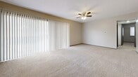 Located at 7018 E Kellogg Dr in Wichita, Kansas, this single-floor home offers three bedrooms and one bathroom within a efficiently arranged floor plan. The layout connects living, kitchen, and sleeping areas through a central hallway, making practical use of the available space.

The kitchen features gray cabinetry, a range with overhead ventilation, a refrigerator, and a granite-style countertop peninsula that provides additional workspace and separation from the adjoining area. Rich hardwood-style flooring runs through the kitchen and living spaces, lending a warm, cohesive look throughout these common areas.

The living room is notably bright, with a large sliding glass door dressed in vertical blinds that allows generous natural light to fill the room. A ceiling fan with integrated lighting adds both comfort and functionality overhead.

The three bedrooms are carpeted and neutral in tone, offering quiet, versatile spaces. The spacious primary bedroom includes a roomy closet with built-in shelving and rod storage, as well as a window with blinds for natural light. The remaining bedrooms are similarly carpeted with neutral walls.

The bathroom features white square tile wainscoting, a toilet, and a tub/shower combination with fully tiled surround and tile flooring, offering a clean, classic aesthetic.