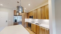 Located at 400 W Swedesford Road in Berwyn, PA, this thoughtfully designed one-bedroom, one-bathroom residence offers a clean, modern aesthetic throughout. The open-concept kitchen and living area serves as the heart of the home, featuring light hardwood-style flooring that enhances the bright, airy feel of the space. The kitchen is a standout, equipped with warm wood cabinetry extending to the ceiling, quartz countertops, a subway tile backsplash, stainless steel appliances including a French door refrigerator, built-in microwave, range, and dishwasher, and stylish pendant lighting above the island counter. The living area is generously proportioned, bathed in natural light from large windows and a private exterior door that opens to an outdoor area. Neutral warm-toned walls complement the light flooring throughout. The bedroom offers a comfortable retreat with soft carpeting, ample wall space, and direct access to a dedicated closet with built-in storage. The bathroom is finished to a high standard, with a wide vanity topped in white quartz, an LED-lit mirror, and a glass-enclosed walk-in shower with white tile surround. Every detail reflects a contemporary and functional design, making this a well-appointed residence in a desirable Berwyn location.