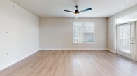 Located at 15506 Interplace Rd in San Antonio, TX, this well-appointed 2-bedroom, 2-bathroom residence offers a thoughtfully designed single-floor layout with a clean, modern aesthetic. The open-concept kitchen and living area serves as the heart of the home, anchored by a large center island with white quartz countertops, a deep undermount sink, and pendant lighting overhead. The kitchen is outfitted with crisp white cabinetry, a subway tile backsplash, stainless steel appliances including a built-in microwave, range, and French door refrigerator, as well as a wine cooler. Light wood-style flooring flows throughout the main living areas, complementing the warm, neutral color palette. The living room opens to the outdoors through French doors with transom windows above, allowing ample natural light to fill the space. Both bedrooms feature plush carpeting and ceiling fans, with large windows offering views of the surrounding area. The primary bedroom connects to a spacious walk-in closet with built-in shelving and hanging rods. The primary bathroom impresses with a lengthy dual-sink vanity, white cabinetry, and wood-look tile flooring. The secondary bathroom includes a tub-shower combination with vertical tile surround and matching white cabinetry. The overall ambiance is bright, clean, and move-in ready.
