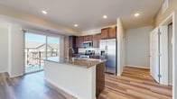 This single-floor residence offers a thoughtfully designed open-concept layout with a cohesive blend of modern finishes throughout. The kitchen serves as a central highlight, anchored by a large island with a granite countertop and an integrated sink. Rich, dark-stained cabinetry provides generous storage, while a full suite of stainless steel appliances — including a French door refrigerator, electric range, and built-in microwave — adds a polished, contemporary feel. Light hardwood-style flooring flows seamlessly from the kitchen into the adjoining living areas, enhancing the sense of openness and continuity.

The living spaces are bright and airy, benefiting from multiple windows dressed with horizontal blinds that allow natural light to flood in. The bedroom features plush neutral carpeting and a window for additional natural light, creating a calm and comfortable retreat. The bathrooms are well-appointed, each featuring granite-topped vanities with dark cabinetry and brushed nickel hardware. One bathroom includes a dual-sink vanity with a large framed mirror, while another offers a shower-tub combination. Recessed lighting throughout maintains a clean, modern aesthetic across the entire residence.