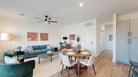 This thoughtfully designed 2-bedroom, 2-bathroom single-story home offers a functional and stylish open-concept layout. The combined living and dining area is bright and welcoming, featuring warm wood-look flooring, crisp white walls, and a modern ceiling fan. Large windows in the living area invite abundant natural light and views of the surrounding neighborhood, creating an airy atmosphere ideal for both relaxing and entertaining.

The kitchen is a standout feature, boasting gray shaker-style cabinetry, white countertops, a classic subway tile backsplash, and stainless steel appliances. A central island with seating provides additional prep space and serves as a natural gathering point, illuminated by elegant globe pendant lights.

The primary bedroom offers a comfortable retreat with a sliding-door closet, wood-look flooring, and clean white walls. The second bedroom is equally well-proportioned, with its own closet and access to a full bathroom. Both bathrooms are finished with gray cabinetry, white countertops, and wood-look flooring. The primary bathroom features a glass-enclosed shower, while the second bathroom includes a tub-shower combination with marble-style tile surround and matte black fixtures throughout. The home's cohesive design elements create a modern yet inviting aesthetic from room to room.