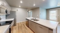 Located at 925 E Omaha St in Rapid City, South Dakota, this single-story, three-bedroom, two-bathroom home offers a well-designed layout with contemporary finishes throughout. The kitchen is a standout feature, equipped with stainless steel appliances including a range, over-the-range microwave, and refrigerator, complemented by taupe cabinetry, light quartz countertops, a double-basin sink, and a central island — all illuminated by recessed ceiling lights. Light wood-style vinyl plank flooring runs consistently through the home, lending a clean, cohesive aesthetic. The three bedrooms are comfortably sized, with neutral gray-toned walls and windows that allow natural light to filter in. The primary bedroom offers a well-proportioned layout suitable for a full bedroom suite. Both bathrooms are finished in a modern style — one features a tub-shower combo with chrome fixtures and a quartz vanity, while the second bathroom includes an open walk-in shower with a safety grab bar. A dedicated laundry room houses a full-size washer and dryer alongside a water heater and overhead wire shelving for additional storage. The home's consistent neutral palette and modern finishes create a clean, functional living environment throughout.