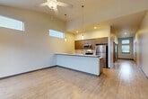 Located in Arlington, WA, this one-bedroom, one-bathroom unit offers a well-designed open-concept layout with modern finishes throughout. The living, dining, and kitchen areas flow seamlessly together beneath impressively tall ceilings, creating an airy and spacious atmosphere. Large windows and transom windows above flood the main living area with natural light, while a ceiling fan adds comfort. Glass doors lead to a private balcony, extending the living space outdoors.

The kitchen is a standout feature, boasting a sleek peninsula with a quartz countertop and undermount sink, warm-toned cabinetry with gold hardware, and a full suite of stainless steel appliances including a refrigerator, range, and over-the-range microwave. Adjacent to the kitchen, a dedicated area houses a stacked in-unit washer and dryer for added convenience.

Light wood-tone flooring runs throughout the main living areas and hallway, while plush carpet lines the bedroom. The bedroom is generously sized, featuring a large closet with contemporary sliding doors and a window that brings in natural light. The bathroom is clean and functional, complete with a full tub/shower combination, modern vanity with warm wood cabinetry, and crisp white fixtures.
