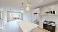 This well-appointed one-bedroom, one-bathroom residence at 128 Elm Street, Unit 304 in Westfield, NJ offers a thoughtfully designed layout across a single floor. Light-toned hardwood flooring runs throughout, lending warmth and visual continuity to the entire space.

The open-concept kitchen and living area serves as the heart of the unit. The kitchen is outfitted with crisp white shaker cabinetry accented by brushed gold hardware, a marble-veined quartz island, and a full suite of stainless steel appliances including a gas range, built-in microwave, dishwasher, and French door refrigerator. A white subway tile backsplash and a gold-finished faucet add refined detail, while pendant lighting overhead enhances the modern aesthetic.

The living area is bright and airy, featuring large sliding glass doors that open to a private balcony with views of the surrounding Westfield streetscape. Multiple windows allow natural light to fill the room throughout the day.

The spacious primary bedroom comfortably accommodates full furnishings and includes access to a closet and a stylish barn door leading to the bathroom. The bathroom showcases a glass-enclosed shower finished in marble-look tile with a built-in niche and penny tile flooring — a standout feature of the unit. A dedicated closet completes the layout.