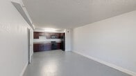 Located at 201 Simpson Rd in Kissimmee, FL, this one-bedroom, one-bathroom unit offers a practical and well-organized layout across a single floor. The open-concept kitchen and living area form the heart of the space, featuring rich dark mahogany cabinetry with ample upper and lower storage, granite-style countertops, a double-basin stainless steel sink, and a full suite of black appliances including a refrigerator, electric range, and built-in microwave. A textured ceiling and under-cabinet lighting add functional character to the kitchen. Durable speckled vinyl flooring runs throughout the main living area and kitchen, offering easy maintenance and a clean, cohesive look. The generously sized bedroom provides comfortable proportions with a window that invites natural light and includes a wall-mounted PTAC heating and cooling unit for individual climate control. A dedicated closet offers convenient storage directly off the bedroom. The bathroom is finished with light tile flooring, a granite-topped vanity with dark wood cabinetry, and a full shower/tub combination with clean white surrounds. Neutral gray walls and white trim throughout the unit create a simple, move-in ready aesthetic well-suited to a variety of furnishing styles.