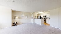 This thoughtfully designed 1-bedroom, 1-bathroom unit offers a practical and comfortable single-floor layout. The open-concept living and dining area is finished with plush neutral carpeting, a ceiling fan, and a large window that invites abundant natural light and outdoor views of the surrounding greenery. The space flows seamlessly into the kitchen, which is separated by a peninsula counter featuring granite-style countertops — ideal for casual dining or entertaining. The kitchen is well-equipped with white cabinetry, stainless steel appliances including a gas range, microwave, refrigerator, and dishwasher, along with wood-look flooring that adds warmth to the space. The bedroom is generously sized, offering soft carpeting, a ceiling fan, a window with natural light, and a dedicated closet with built-in shelving for convenient storage. The bathroom features wood-look flooring, a white vanity with granite-style countertops, a large mirror with overhead lighting, and clean, neutral finishes throughout. A separate closet near the entryway provides additional storage. The unit maintains a cohesive, neutral color palette throughout, creating a bright and welcoming atmosphere.